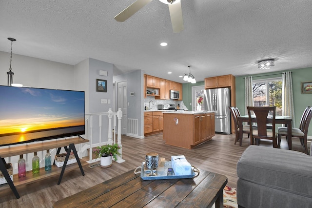 living room featuring dark wood-type flooring, ceiling fan, sink, and a textured ceiling