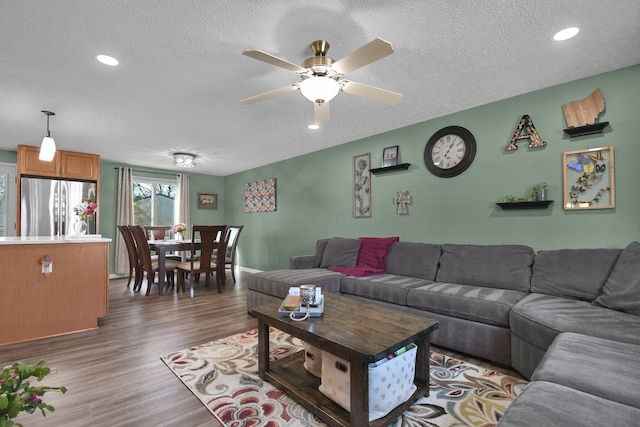 living room featuring ceiling fan, a textured ceiling, and dark hardwood / wood-style flooring