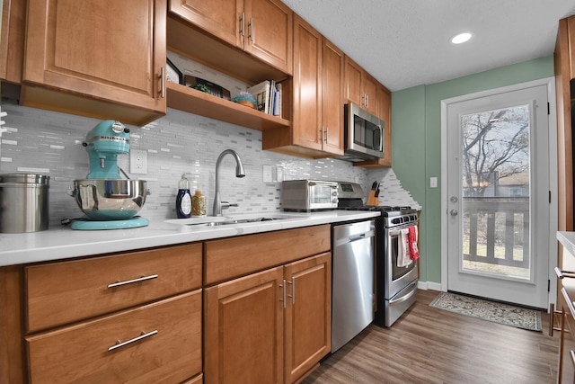 kitchen featuring sink, tasteful backsplash, light hardwood / wood-style flooring, a textured ceiling, and stainless steel appliances