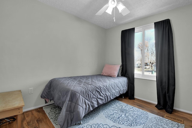 bedroom with ceiling fan, hardwood / wood-style floors, and a textured ceiling