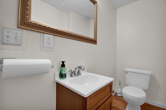 bathroom with vanity, wood-type flooring, a textured ceiling, and toilet