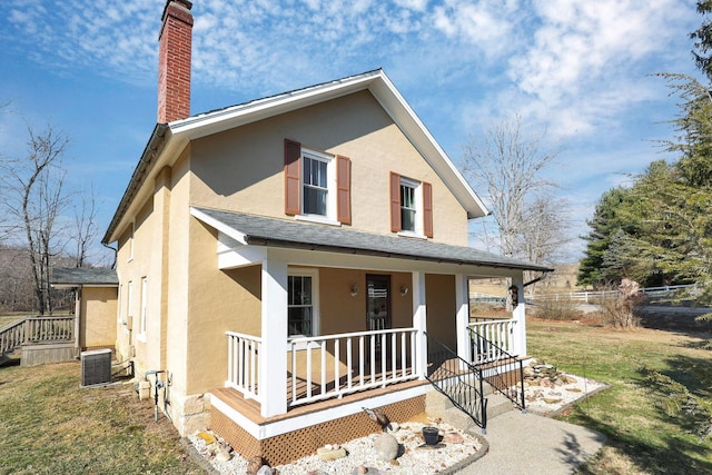 view of front of house featuring a porch, central AC unit, and a front lawn