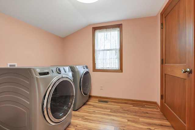 clothes washing area featuring separate washer and dryer and light hardwood / wood-style floors