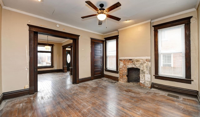 unfurnished living room featuring crown molding, a stone fireplace, hardwood / wood-style floors, and a wealth of natural light