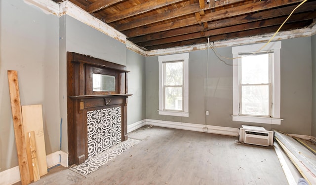 unfurnished living room featuring a wall mounted AC and hardwood / wood-style floors