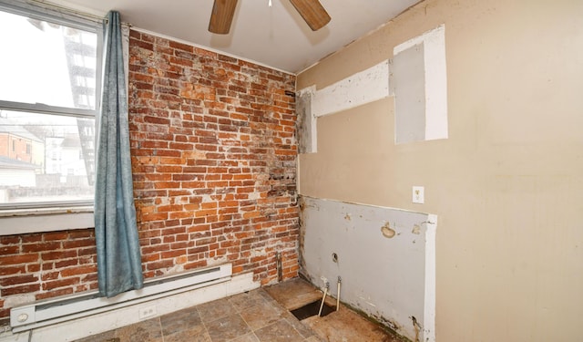 washroom featuring baseboard heating, ceiling fan, and brick wall