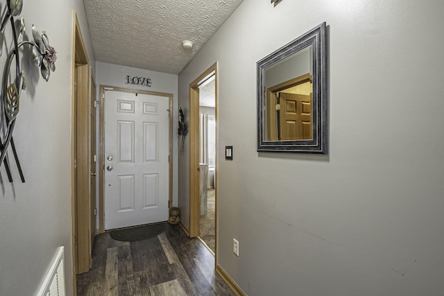 doorway to outside featuring a textured ceiling and dark hardwood / wood-style flooring