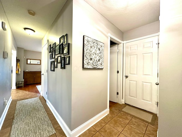 hallway featuring tile patterned flooring and a textured ceiling