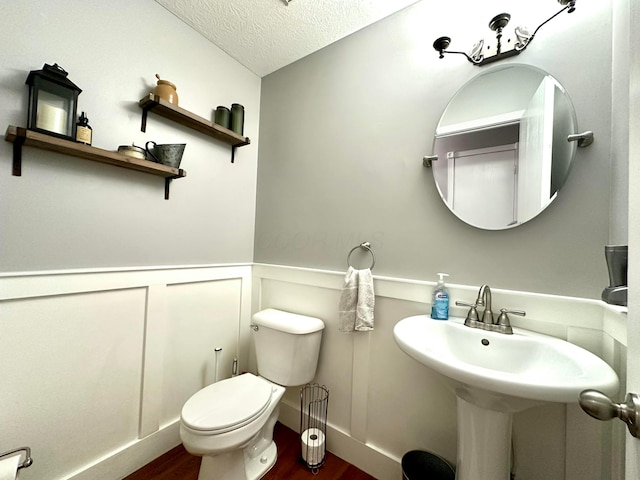 bathroom with wood-type flooring, toilet, and a textured ceiling