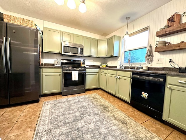 kitchen with light tile patterned floors, stainless steel appliances, a textured ceiling, and green cabinets