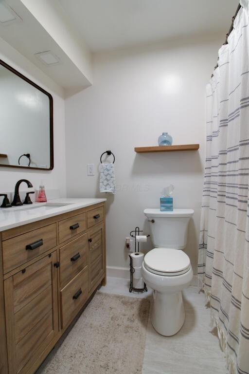 bathroom featuring vanity, curtained shower, and toilet