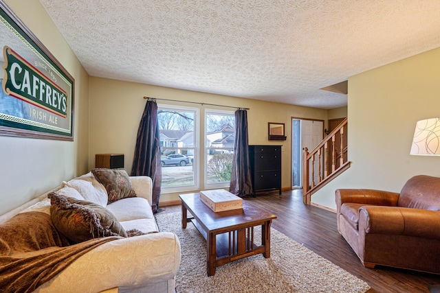 living area with stairs, a textured ceiling, wood finished floors, and baseboards