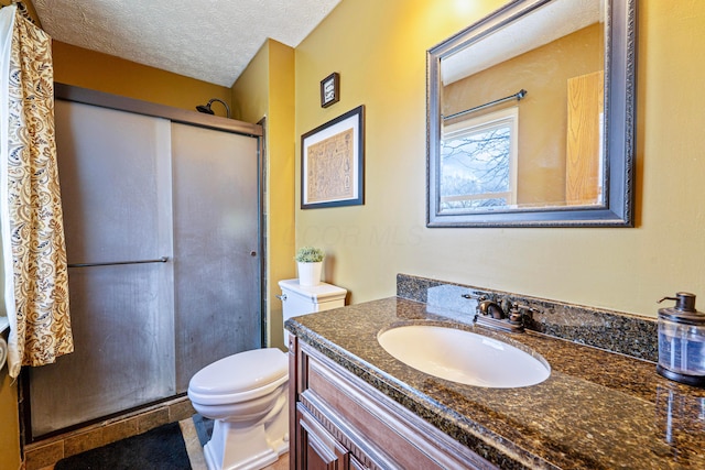 bathroom featuring toilet, a shower stall, a textured ceiling, and vanity