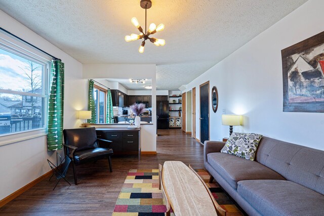 living area featuring baseboards, a chandelier, dark wood finished floors, and a textured ceiling