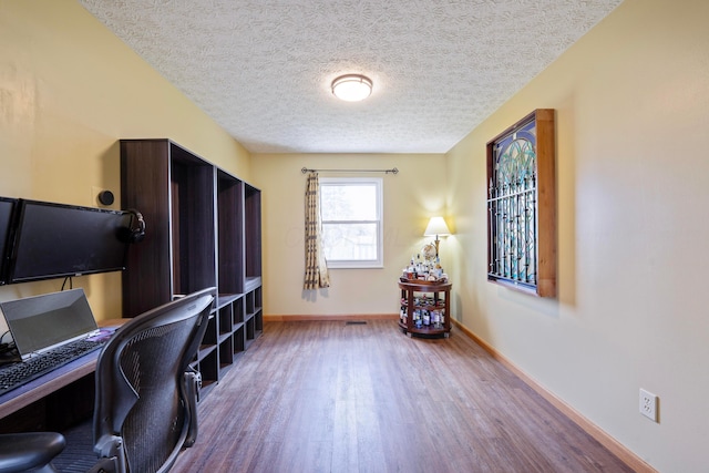 office area with a textured ceiling, wood finished floors, and baseboards