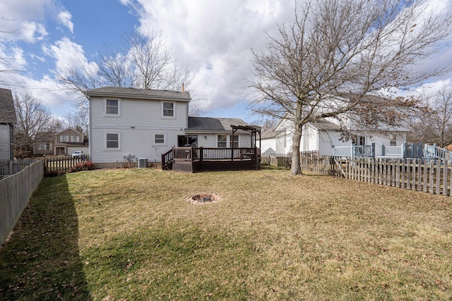 back of property featuring a fenced backyard, central air condition unit, a fire pit, a yard, and a wooden deck