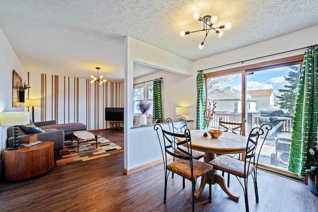 dining area with a chandelier, a textured ceiling, wood finished floors, and baseboards