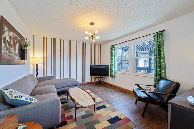 living room with a chandelier, a textured ceiling, baseboards, and wood finished floors