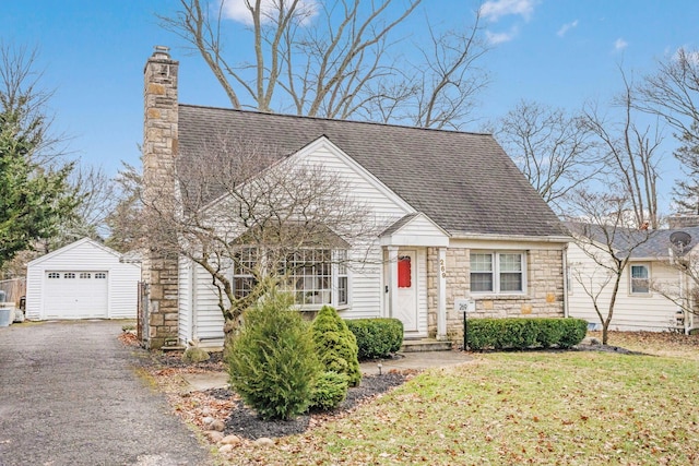 new england style home with a garage, an outbuilding, and a front yard