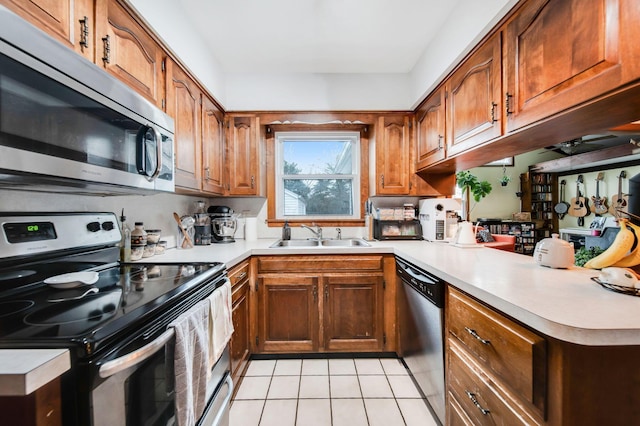 kitchen featuring appliances with stainless steel finishes, sink, light tile patterned floors, and kitchen peninsula