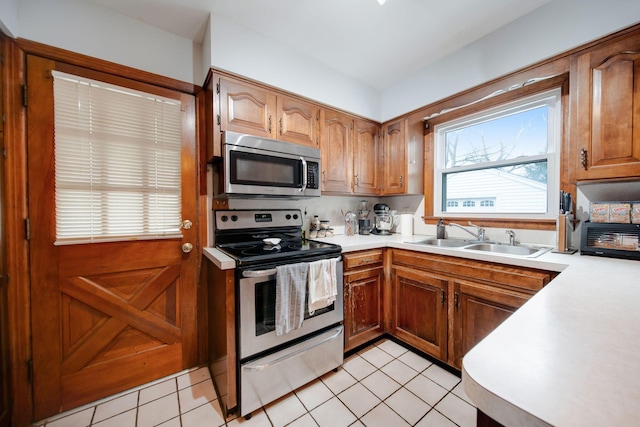 kitchen with sink, light tile patterned floors, and stainless steel appliances