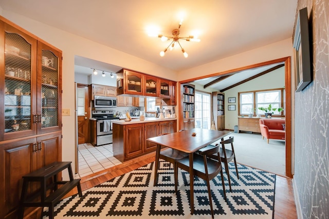 dining space featuring an inviting chandelier, light hardwood / wood-style floors, and vaulted ceiling