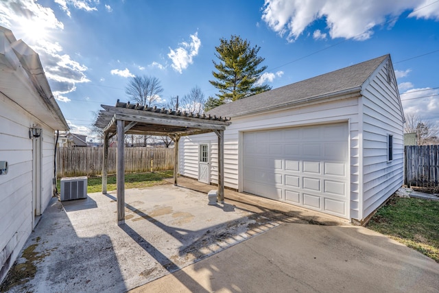 detached garage with driveway, fence, and central AC unit