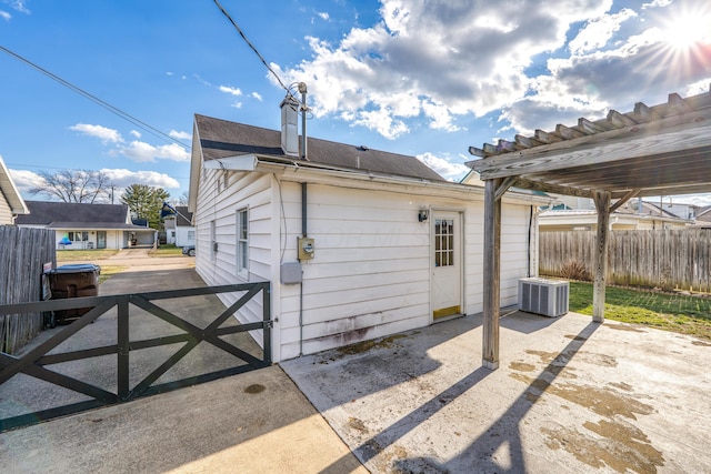 back of house with roof with shingles, a chimney, central AC unit, a patio area, and fence