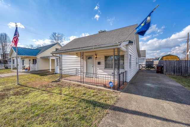 bungalow-style house featuring covered porch, roof with shingles, a front yard, and fence