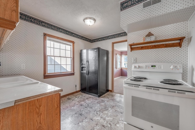 kitchen with visible vents, light countertops, black refrigerator with ice dispenser, electric range, and wallpapered walls