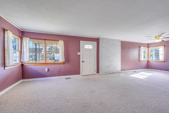 carpeted spare room featuring ceiling fan, visible vents, baseboards, and ornamental molding