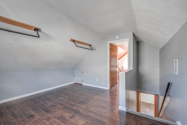 bonus room with a textured ceiling, baseboards, vaulted ceiling, and dark wood-type flooring