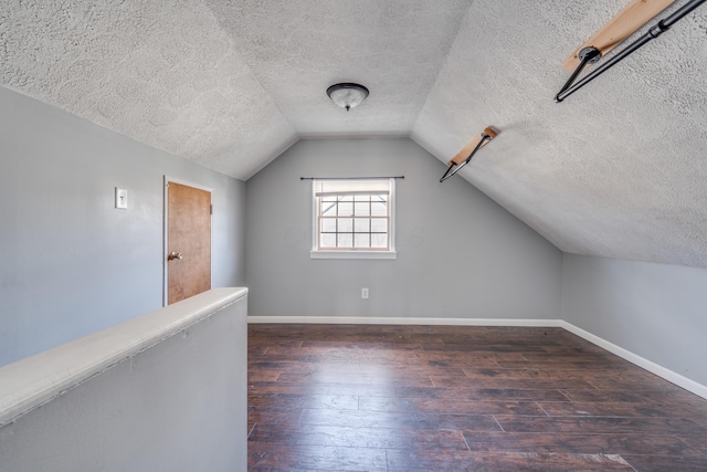 bonus room featuring lofted ceiling, a textured ceiling, dark wood finished floors, and baseboards