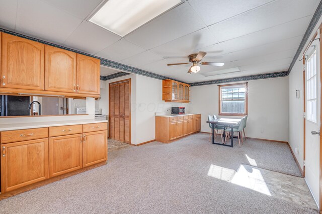 kitchen featuring a drop ceiling, light carpet, baseboards, light countertops, and glass insert cabinets