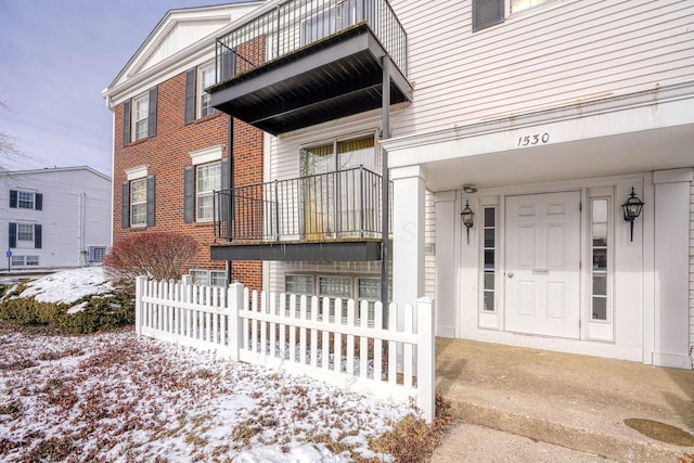 snow covered property entrance featuring a balcony