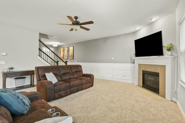 carpeted living room with a tile fireplace and ceiling fan