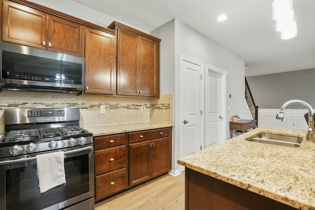 kitchen featuring sink, backsplash, stainless steel appliances, and light stone countertops