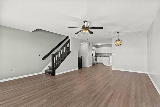 unfurnished living room with dark wood-type flooring, a textured ceiling, and ceiling fan