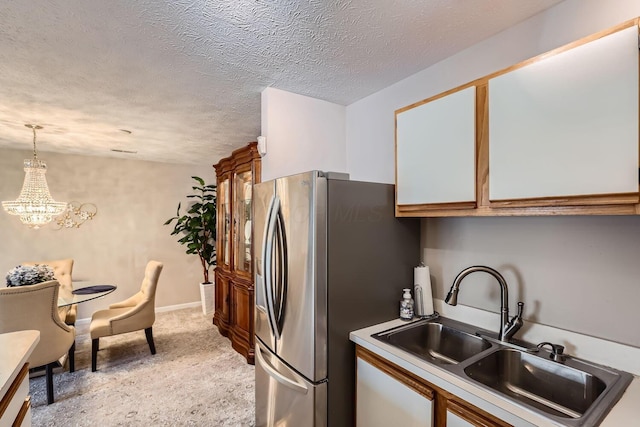 kitchen featuring decorative light fixtures, sink, stainless steel fridge, light carpet, and a textured ceiling