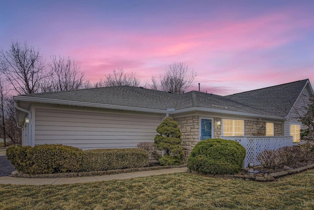 property exterior at dusk featuring a lawn