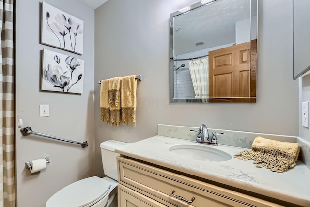 bathroom featuring vanity, curtained shower, and toilet