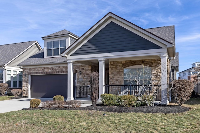 view of front of home featuring an attached garage, covered porch, stone siding, concrete driveway, and roof with shingles