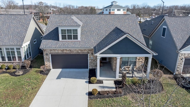 view of front of home featuring a shingled roof, a porch, a garage, stone siding, and driveway