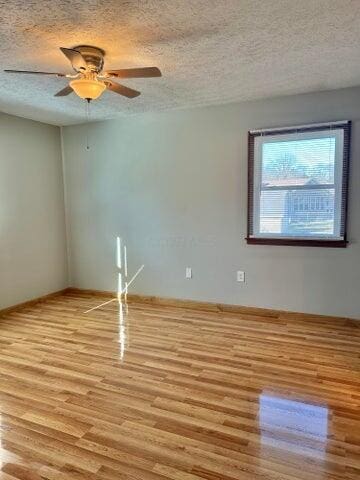 unfurnished room with a ceiling fan, light wood-type flooring, and a textured ceiling