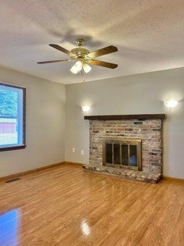 unfurnished living room with visible vents, a fireplace, a textured ceiling, and wood finished floors