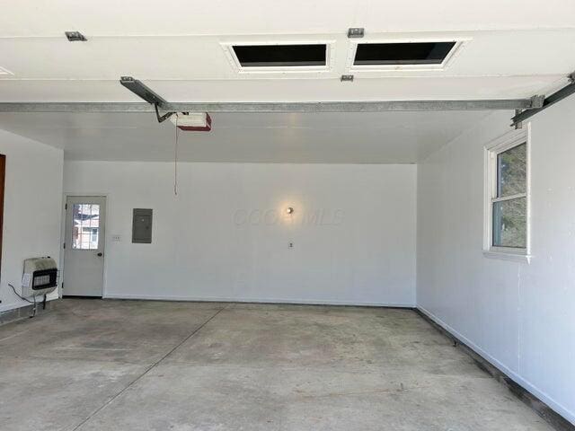 garage with electric panel, heating unit, and a garage door opener