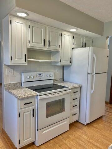 kitchen with tasteful backsplash, light wood-style flooring, and white appliances