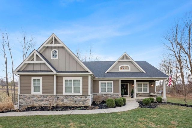 craftsman-style home with a porch, stone siding, roof with shingles, board and batten siding, and a front yard