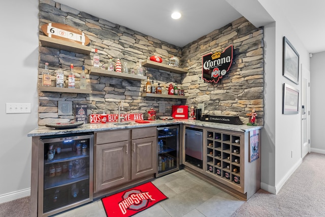 bar with beverage cooler, baseboards, a sink, and wet bar