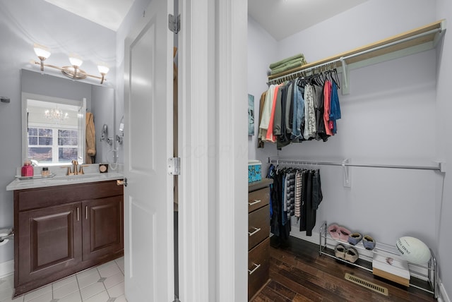 spacious closet featuring a notable chandelier, visible vents, and a sink